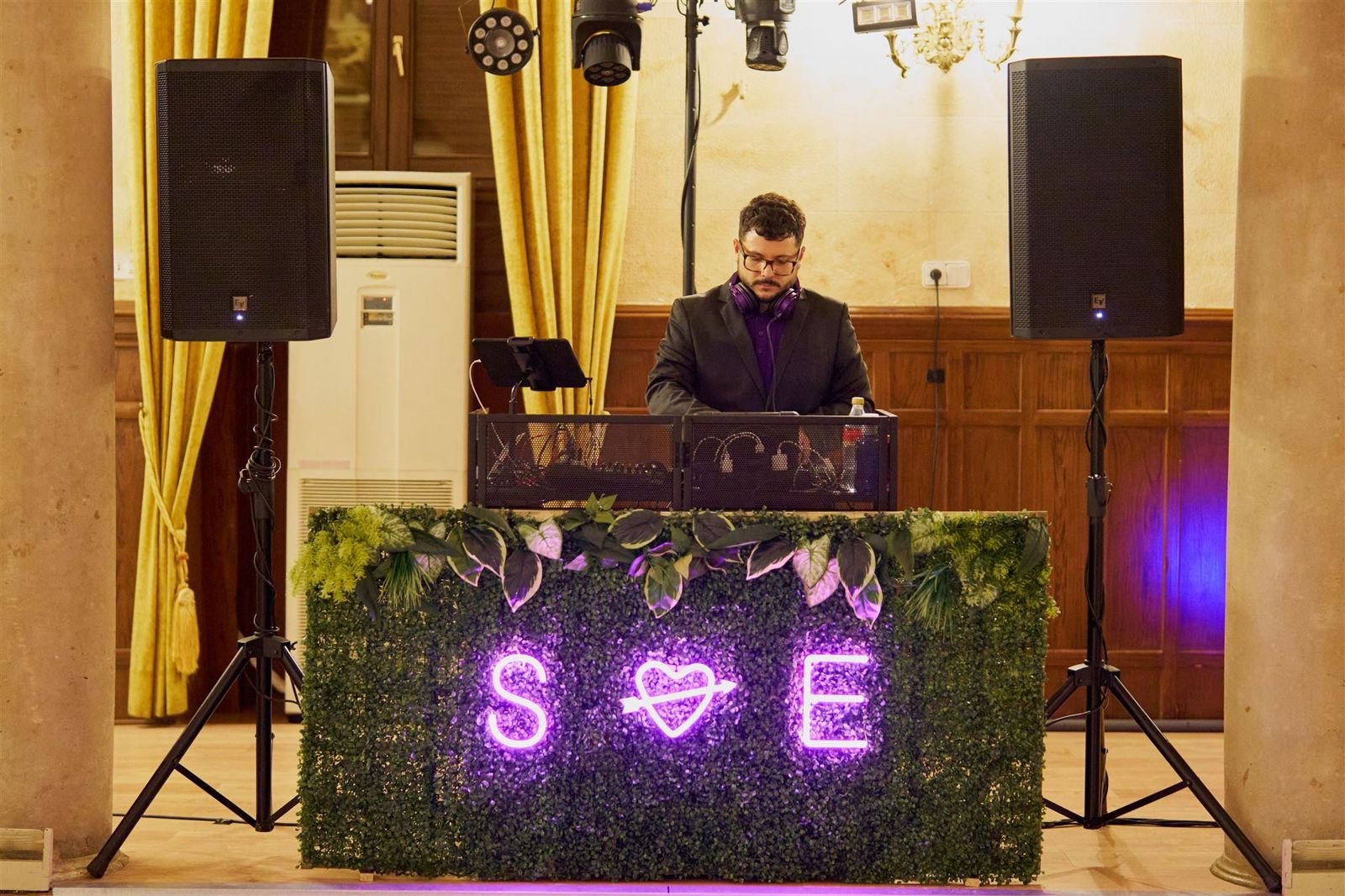 Cabina de DJ en un salón de boda con las iniciales de los novios en neón