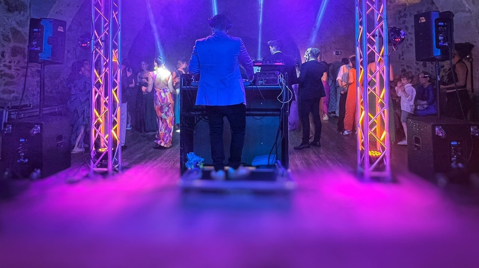 Pista de baile llena con luces violetas y estructuras de iluminación
