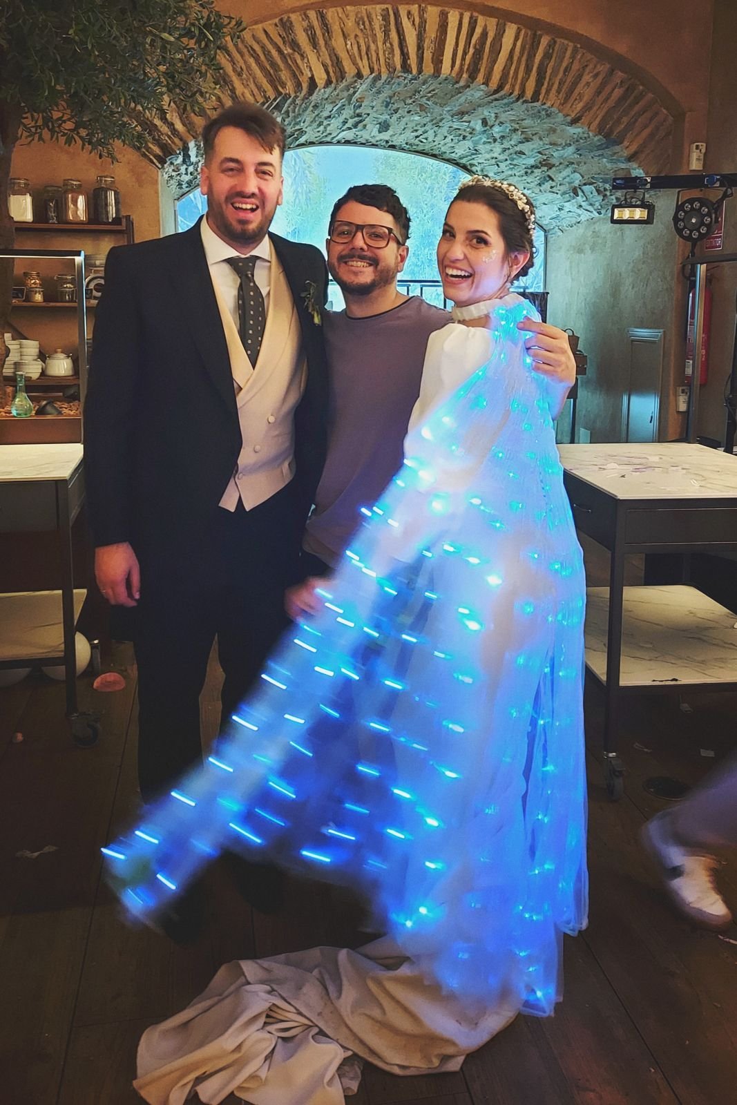 Javi con una pareja de novios; la novia lleva una capa con luces LED